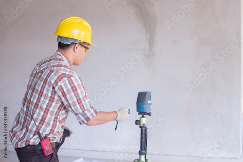 Worker in measuring wall with laser leveler at construction site, Engineers at work checking construction building project with laser level machine during measurement work on site