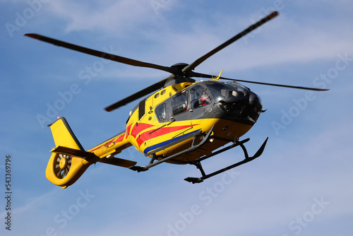 Żółty helikopter na niebieskim niebie w powietrzu.  photo