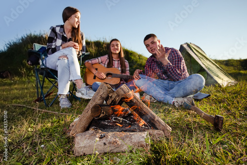 Young people having picnic, girl playing guitar (Front focus)
