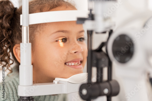 Vision, test and girl for eye exam in the opthalmologist office with equipment for glasses. Optics, examination and female child testing for eyecare health or wellness for optometry for healthcare photo