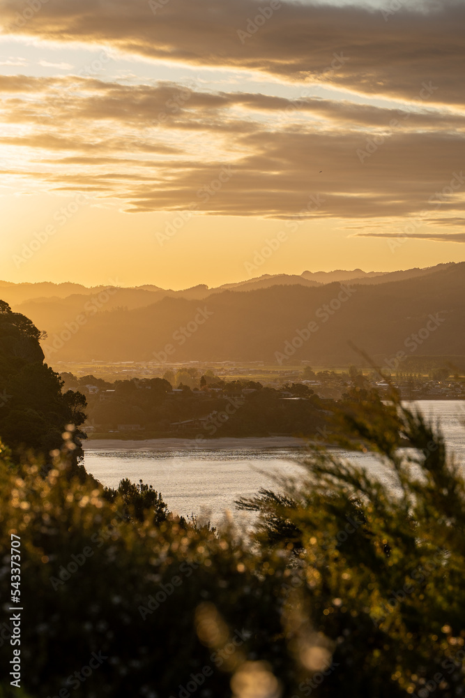 Sunset over New Zealand mountains with sail boat passing by