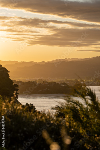 Sunset over New Zealand mountains with sail boat passing by