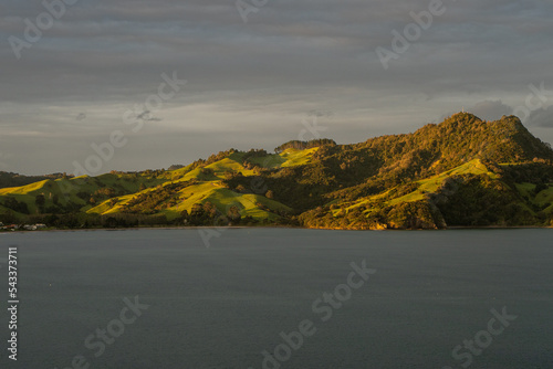 Sunset over New Zealand mountains with sail boat passing by photo