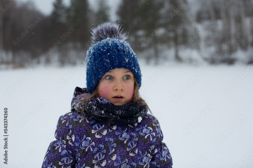 A girl in winter on the street with rosy cheeks and a surprised expression on her face A girl in winter on the street with rosy cheeks and a surprised expression on her face