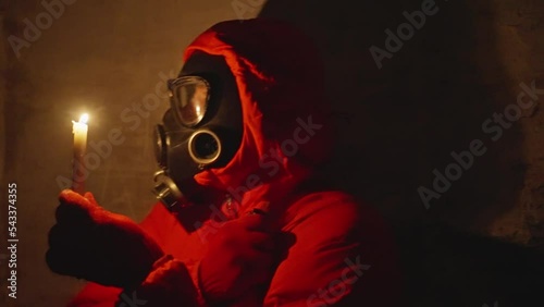 Ukraine war. Shelter. Bunker, nuclear war, a man in a gas mask and protective clothing is hiding in a bomb shelter, electricity is turned off, a man is lighting a candle, he is scared photo