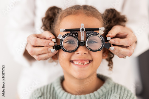 Eye, vision and test with child for glasses in optometry office for eye care and health. Eyewear, exam and medical opthalmology with little girl testing for lenses and frames diagnosis for optics photo