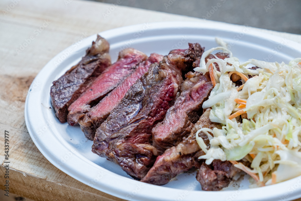 Cooked rib eye steak cut into pieces and served with kou slow salad of cabbage and carrots.