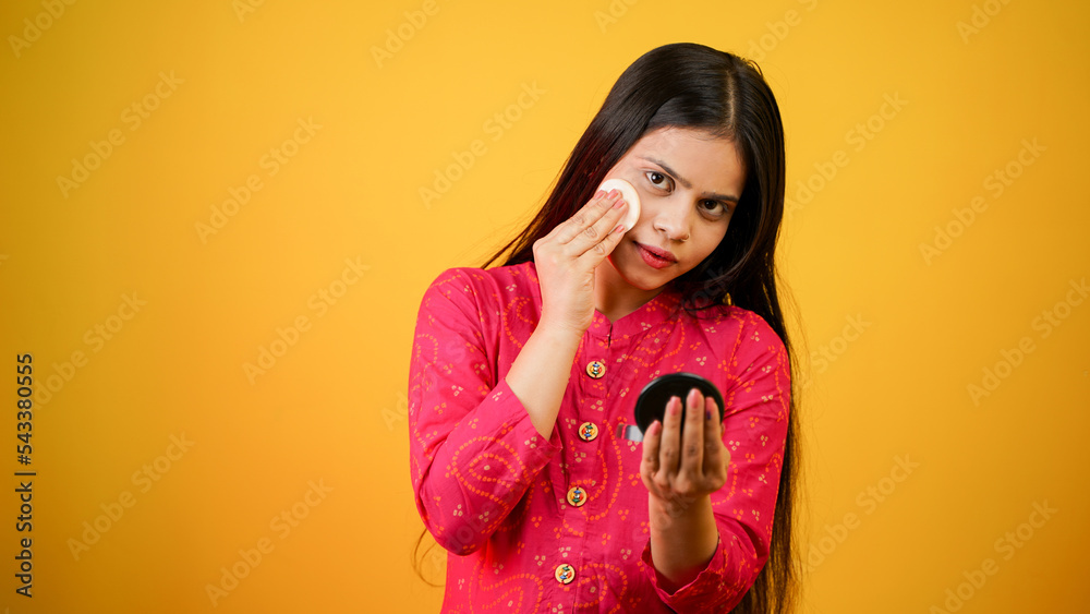 Obraz premium Beautiful young Indian woman holding cotton pads near face. Photo of woman with perfect skin on white background. Beauty and skin care concept