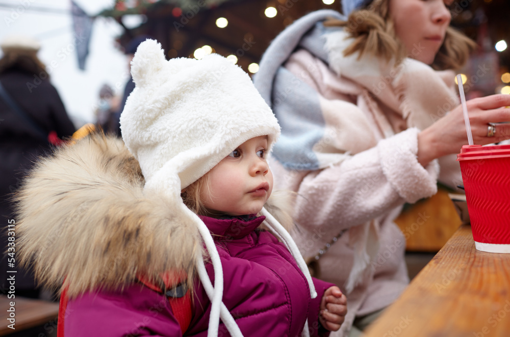 Mother and daughter are walking around the city on Christmas and New Year holidays. Parent and little child having fun outdoors Mother and daughter are walking around the city on Christmas and New Year holidays. Parent and little child having fun outdoors