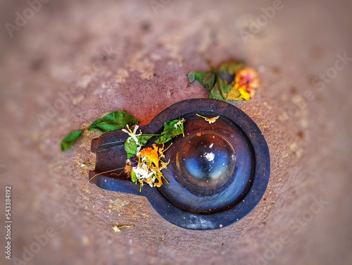 A small, black shiva-lingam made from stone and covered in flowers and bel leaves. Hindu people offer prayers to shiv linga, symbolic form of God Shiva at Kunkeshwar  temple, sindhudurga, India.