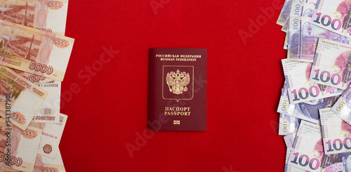 Banner with paper banknotes, Georgian lari and Russian biometric passport on a red textile background. 5000 rubles and 100 GEL. Cash for currency exchange. The concept of immigration and relocation