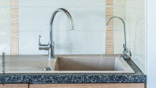 Modern interior of kitchen in apartment. Close-up of granite sink. Two water taps. Faucet for filtered water.