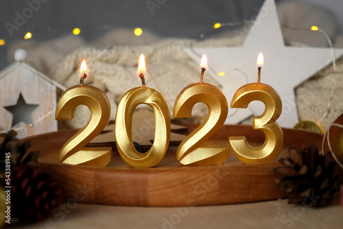 New Year 2023 Golden Numbers Candles is Burning. Blurred Lights in the Background. Happy New Year Holidays Card with Gifts, Decorations. Bows and Confetti. Modern Festive Creative Greeting Card Design