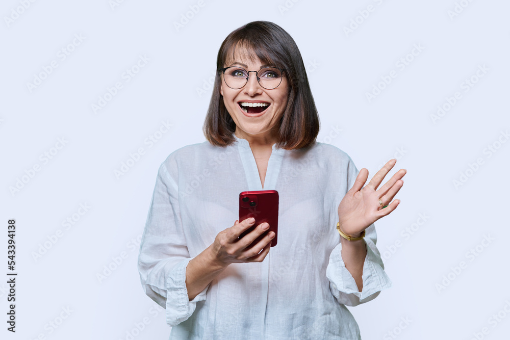Portrait of middle aged woman with phone looking at camera on white background Portrait of middle aged woman with phone looking at camera on white background