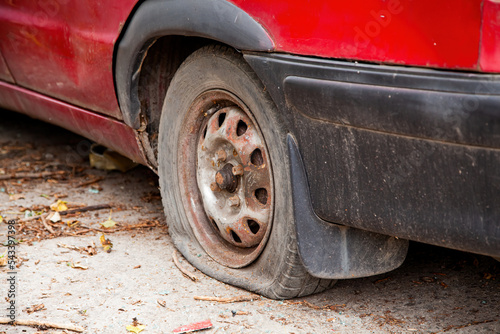 A flat tyre on a car. Flat car tire close up, punctured wheel. Red car with a broken tire