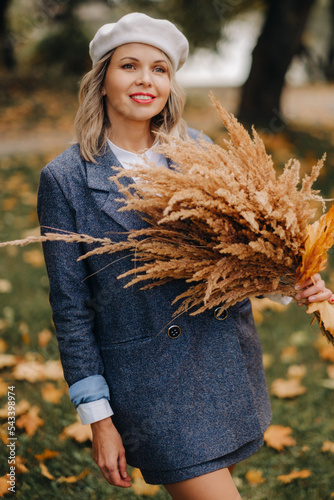 Fotografia Portrait of a Girl in a jacket and birette with an autumn bouquet in an autumn p