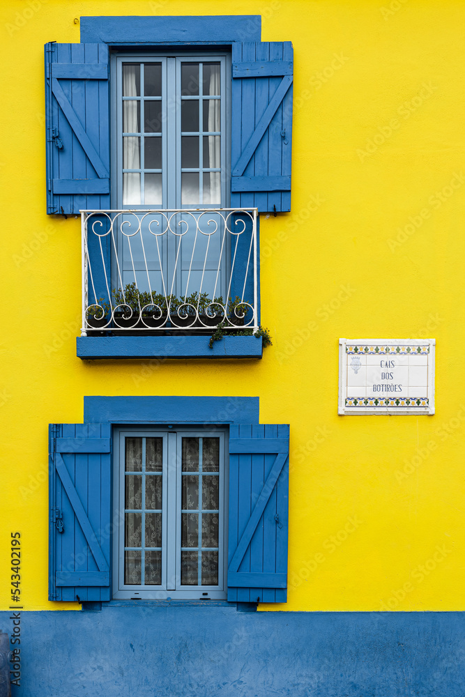 yellow facade and windows with blue  shutters
