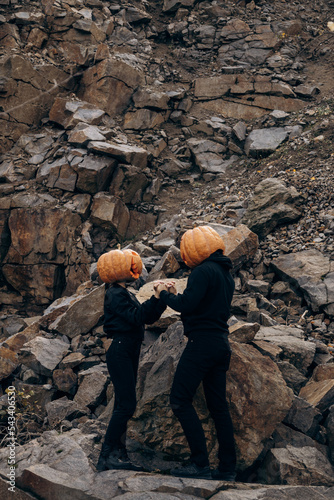 Halloween holiday lovers stand in a pumpkin on their heads