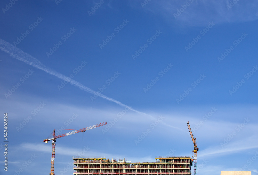 Budowa apartamentowca w Katowicach dźwigi budowlane i elewacja podczas budowy na tle błękitnego nieba - obrazy, fototapety, plakaty 