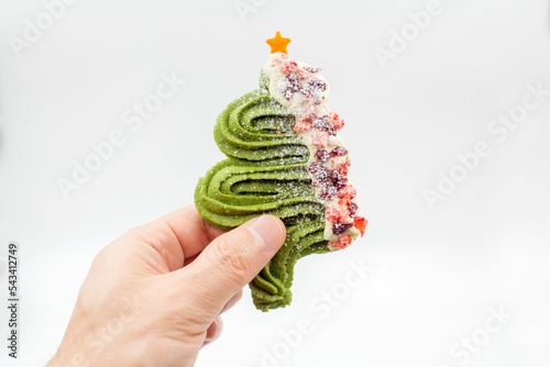 Person's hand holding Christmas tree cookie against white background