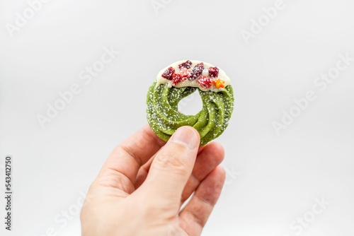 Person's hand holding a round Christmas cookie against a white background