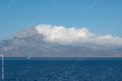 View of the Aegean Island of Samos from the sea with white clouds over the mountains