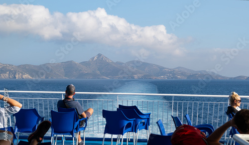 Tourists sitting on the deck of a ferry ship through the Aegean Sea from Samos