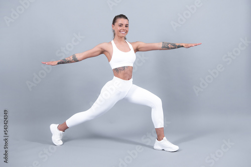 Beautiful strong happy cheerful sports woman posing on isolated background. Happy young woman in sports clothing smiling. Muscular fitness model.