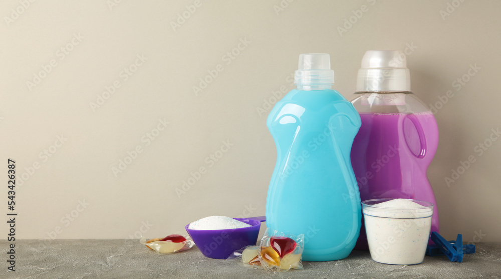 Laundry detergents with washing powder and capsules on grey background. Space for text Laundry detergents with washing powder and capsules on grey background. Space for text