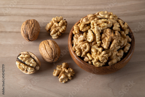 Peeled walnuts and whole walnuts in wooden bowl 