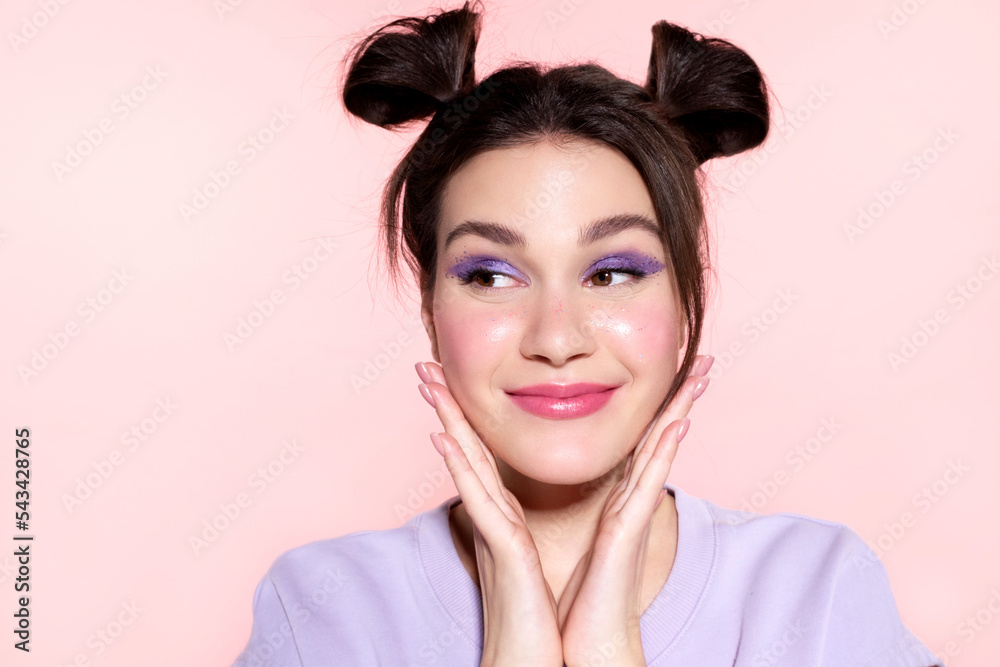Funny  young teen  girl with hair buns and  colored makeup. Make-up cosmetics products advertising