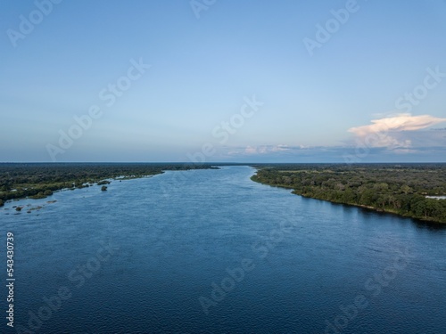 Aerial shot of the lake between lush trees against a blue sky photo