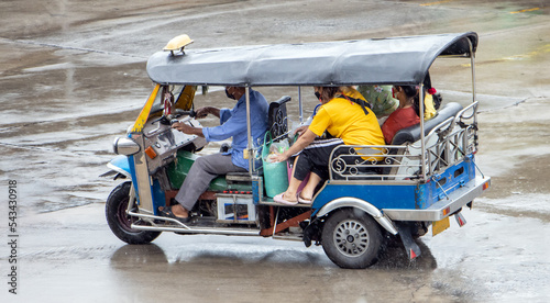 Wallpaper Mural A traditional motor tricycle - tuk tuk full of passenger rides in a rain, Thailand Torontodigital.ca
