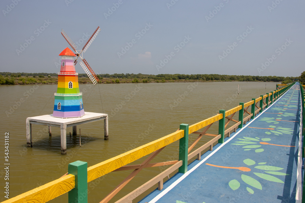 Decorative model of a windmill beside a trail with a wooden railing over the coast
