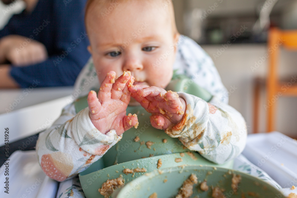 six-month-old-baby-looking-at-hands-covered-in-weetbix-breakfast-food