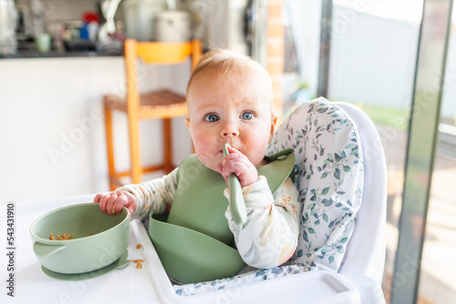 Unsure baby with wide eyes tasting weetbix food for breakfast photo