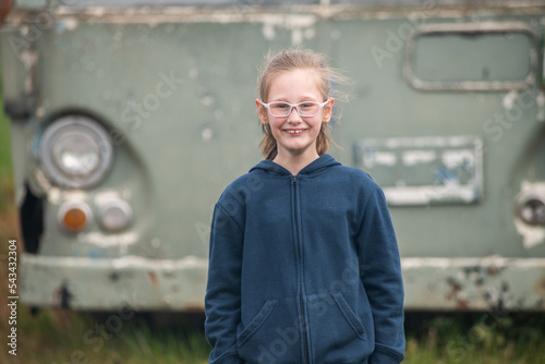 Ten year old girl stands in front of old bus. photo