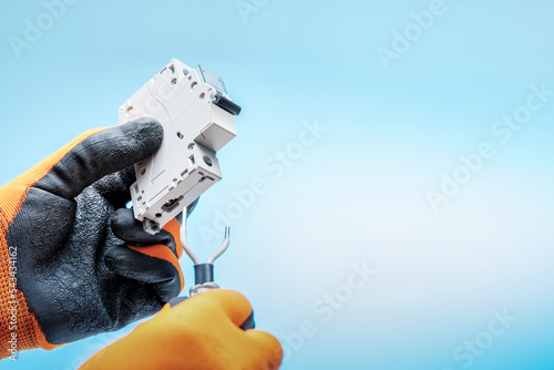 Electrician changing or installing an electrical switch. Male hands in protective gloves holds swith and cables. photo