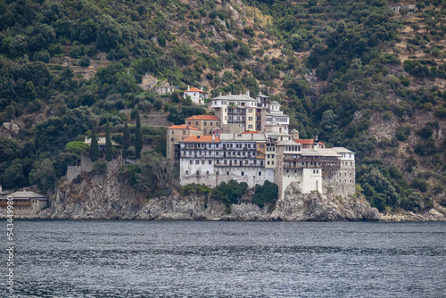 Scenic view from boat on Osiou Gregoriou Monastery at Mount Athos, Chalkidiki, Central Macedonia, Greece, Europe. Eastern Orthodox terrain of Again Oros. Landmark build on coastline rock formation photo