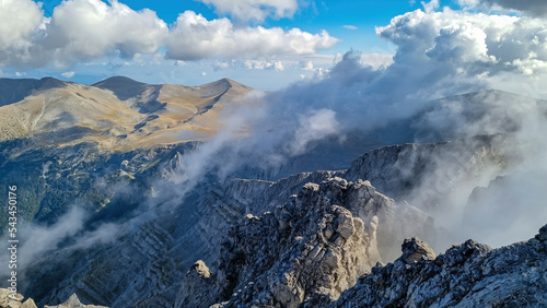 Panoramic view of the cloud covered slopes and rocky ridges of Pieria Mountains near Mount Olympus in Mt Olympus National Park, Macedonia, Greece, Europe. Trekking on hiking trail through mystical fog photo