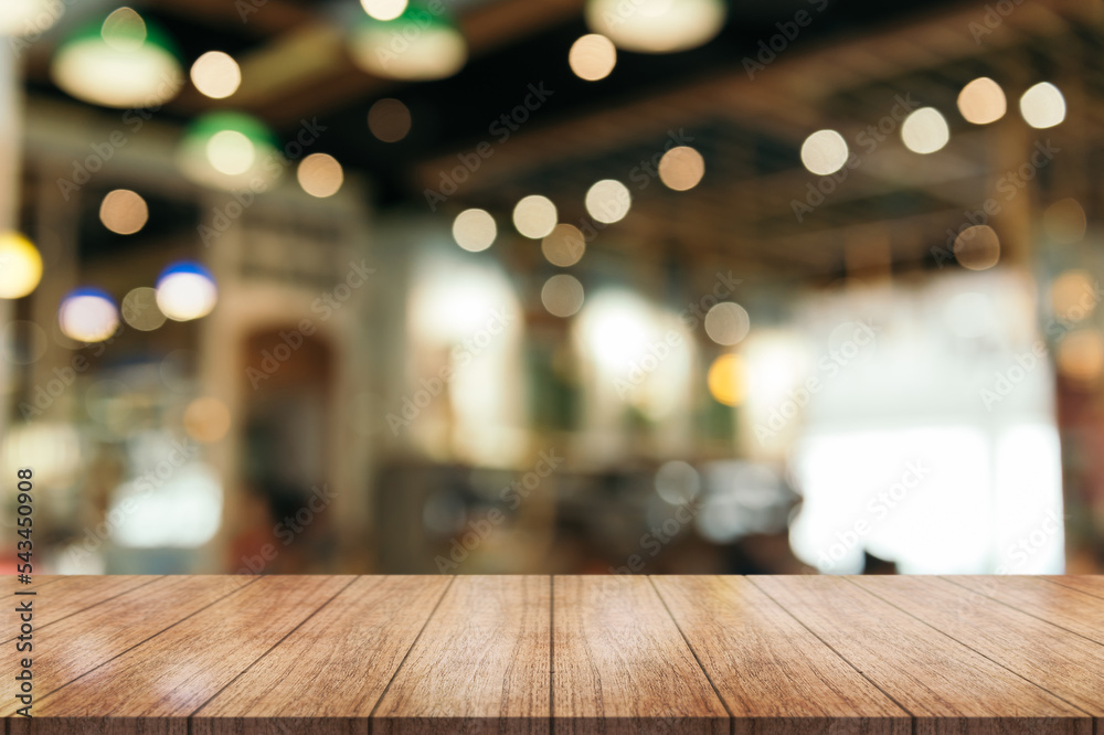 Empty wooden table top with lights bokeh on blur restaurant background.