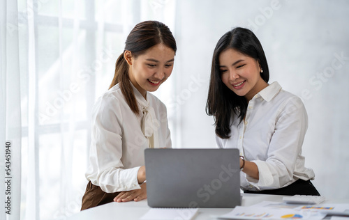 Two young Asian businesswomen talk, consult, discuss working with new startup project idea presentation analyze plan marketing and investment in the office.