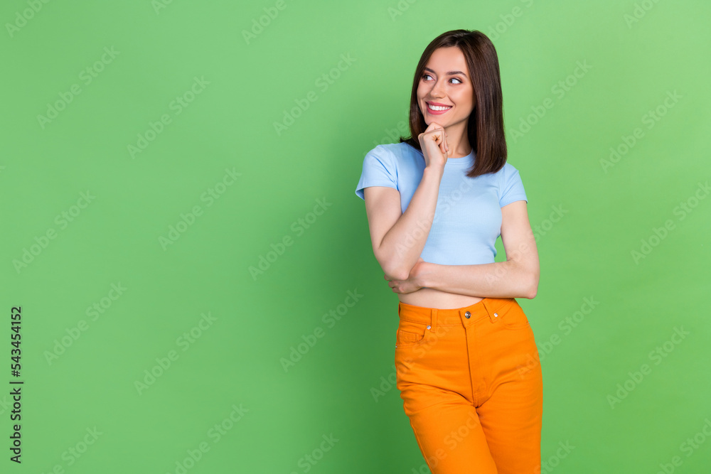 Photo of positive pretty person hand touch chin look interested empty space isolated on green color background Photo of positive pretty person hand touch chin look interested empty space isolated on green color background
