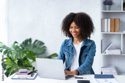 Attractive smiling African American businesswoman using laptop at office
