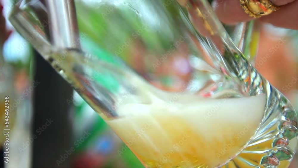 Copo de Chopp amarelo se enchendo numa tarde de Verão com pessoas ao Fundo em volta da piscina