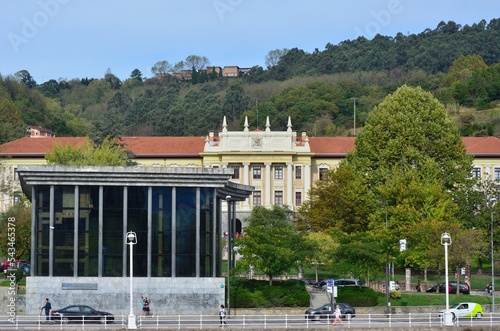 Universidad Comercial en Bilbao tapada por un edificio acristalado y arboles y detras la escuela de hosteleria en una pequeña colina photo