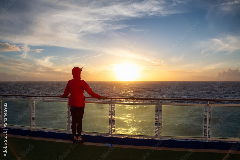 Fototapeta premium Adventure woman traveler enjoying colorful sunset from a Cruise Ship. North Atlantic Ocean. Travel Concept