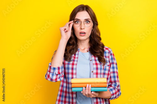 Portrait of clever impressed woman curly hairstyle checkered shirt hold book fingers touch glasses isolated on yellow color background