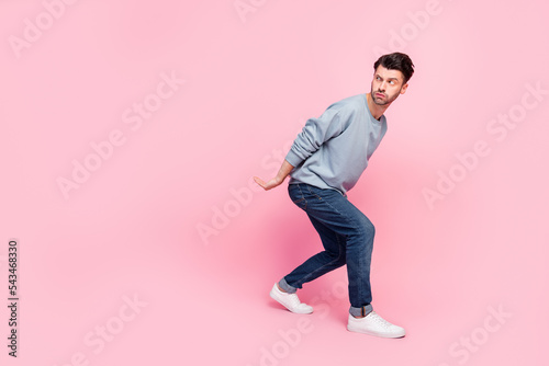 Full body photo of nice young man hold heavy box look suspicious empty space wear stylish blue clothes isolated on pink color background photo