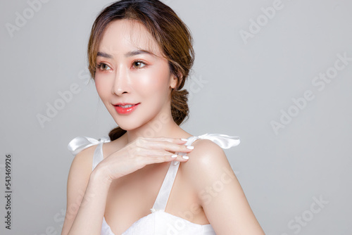 Asian woman with a beautiful face and Perfect clean fresh skin. Portrait of female model with natural makeup and sparkling eyes on Grey isolated background. Cosmetology, Body care, plastic surgery.